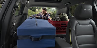 Un hombre cargando equipo de acampar en el interior de la cajuela de la Chevy Trailblazer 2026