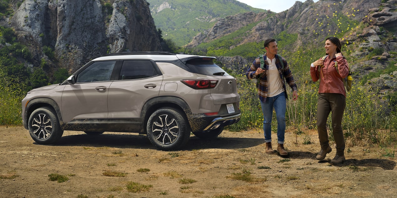 Una pareja haciendo senderismo en la montaña con su Chevy Trailblazer 2026