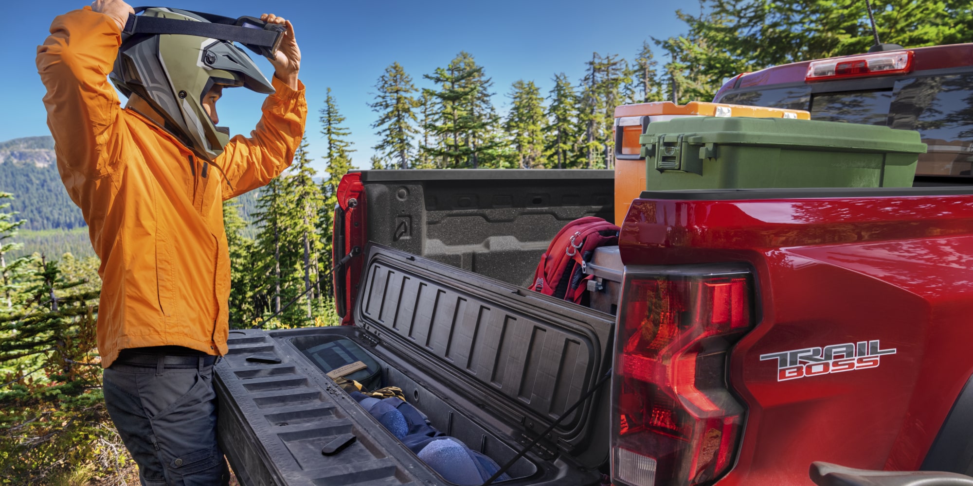 A Person with Helmet Is Checking the Cargo of a Red 2026 Chevy Colorado Pickup Truck