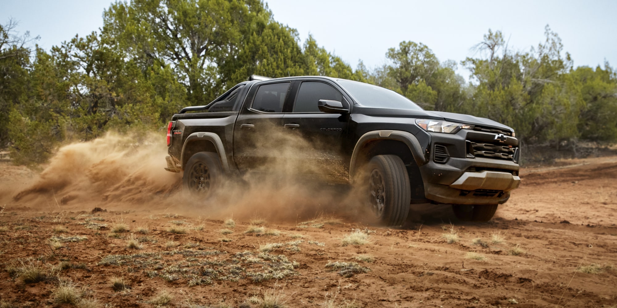 2026 Chevrolet Colorado Trail Boss Midnight Edition shown in black, featured in a rural setting in a 3/4 front passenger-side view while off-roading.