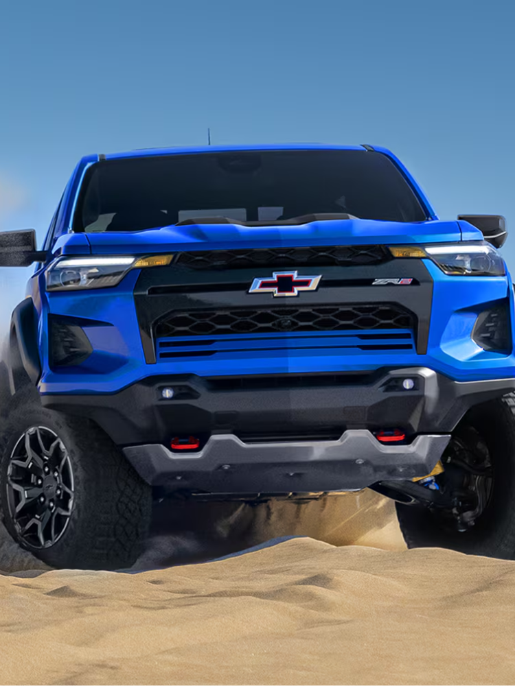 Driver side view of a 2026 Chevy Silverado EV parked in the mountains