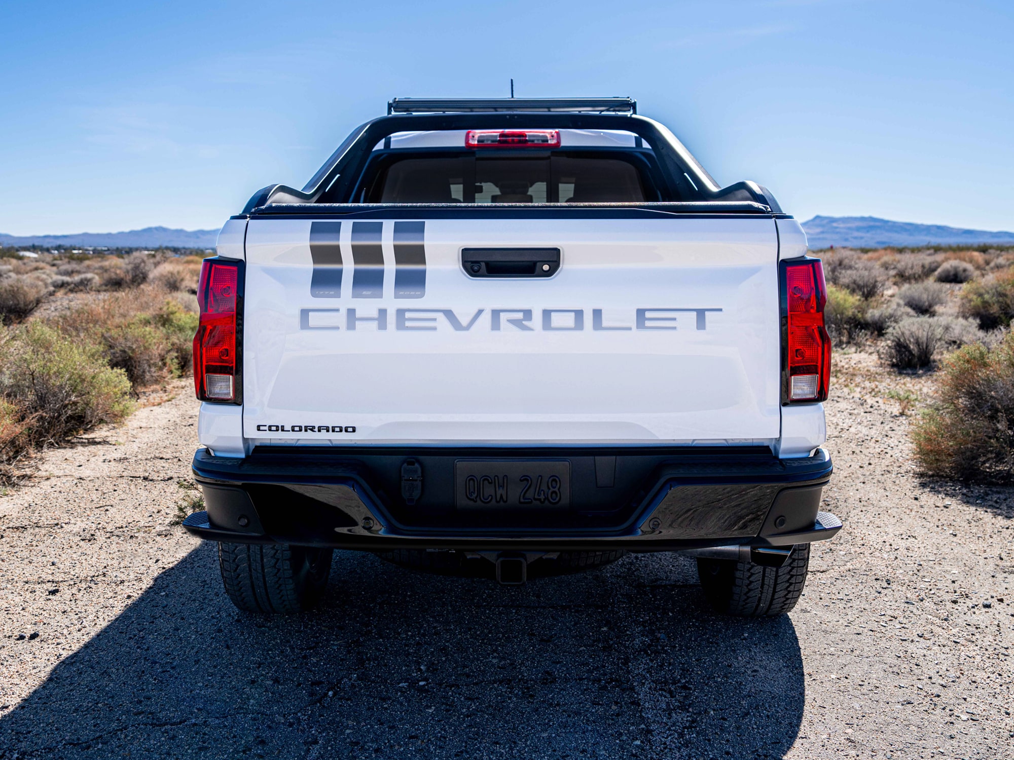 The Rear View of a White Chevrolet Colorado Stars and Steel Truck, Featuring Stripes on the Tailgate.