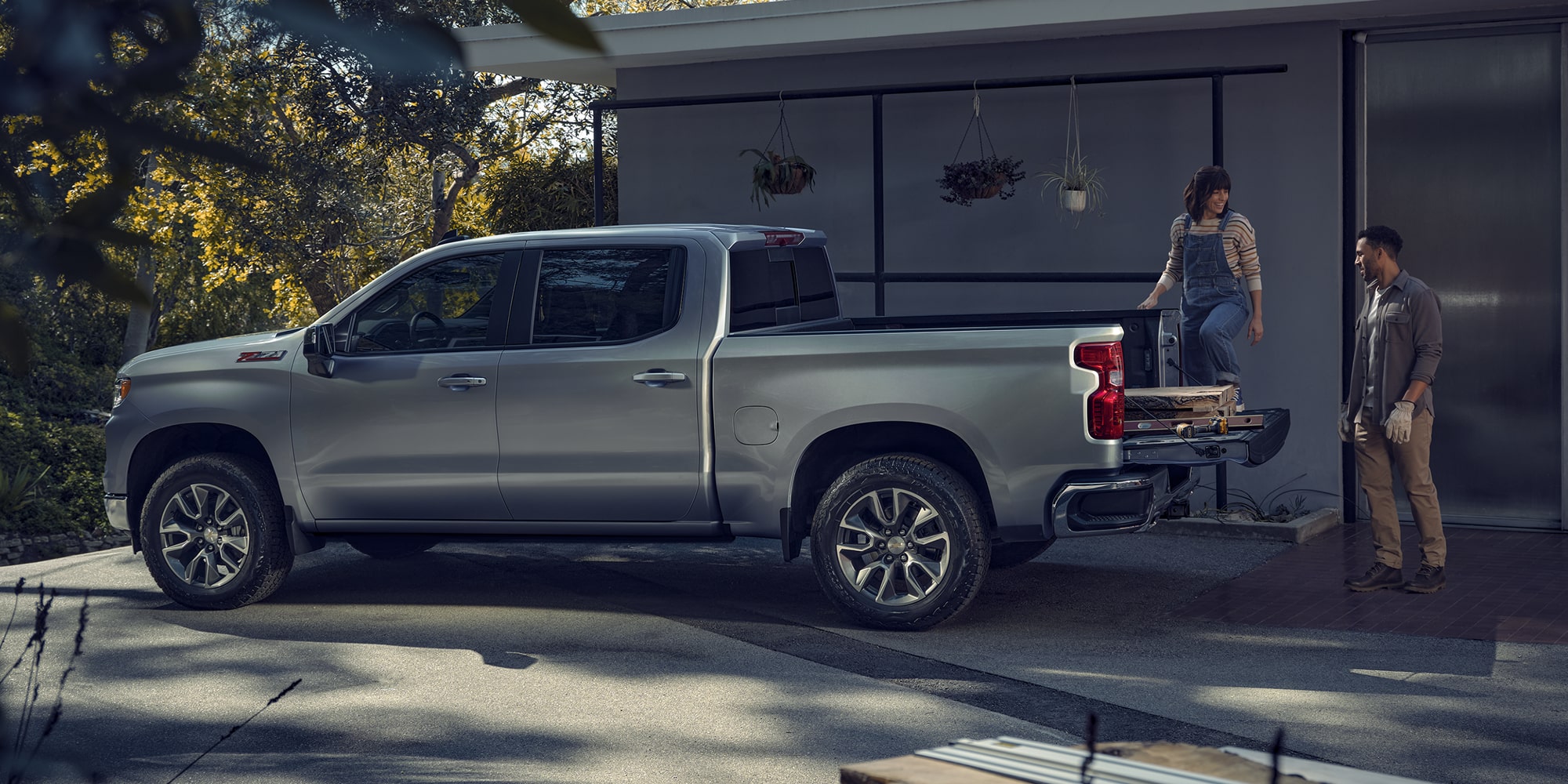 Side view of the 2026 Chevrolet Silverado LD Crew Cab LT parked beside a house.