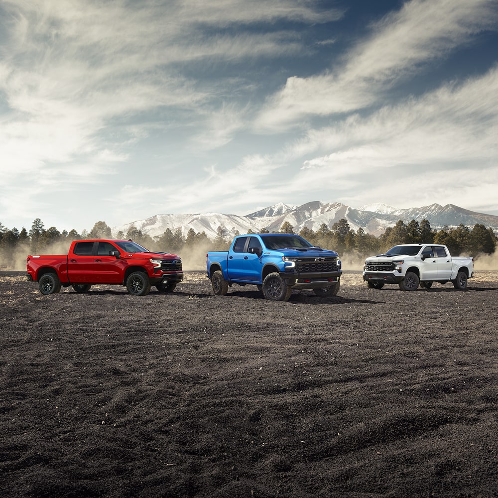Three Chevrolet Silverado trucks parked outdoors.