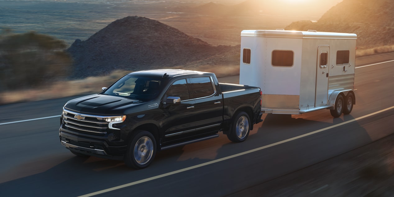 2026 Chevrolet Silverado LD towing a trailer by a beachside road.