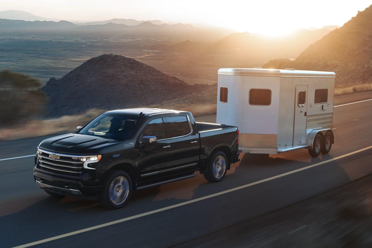 2026 Chevrolet Silverado LD towing an enclosed trailer on the road.