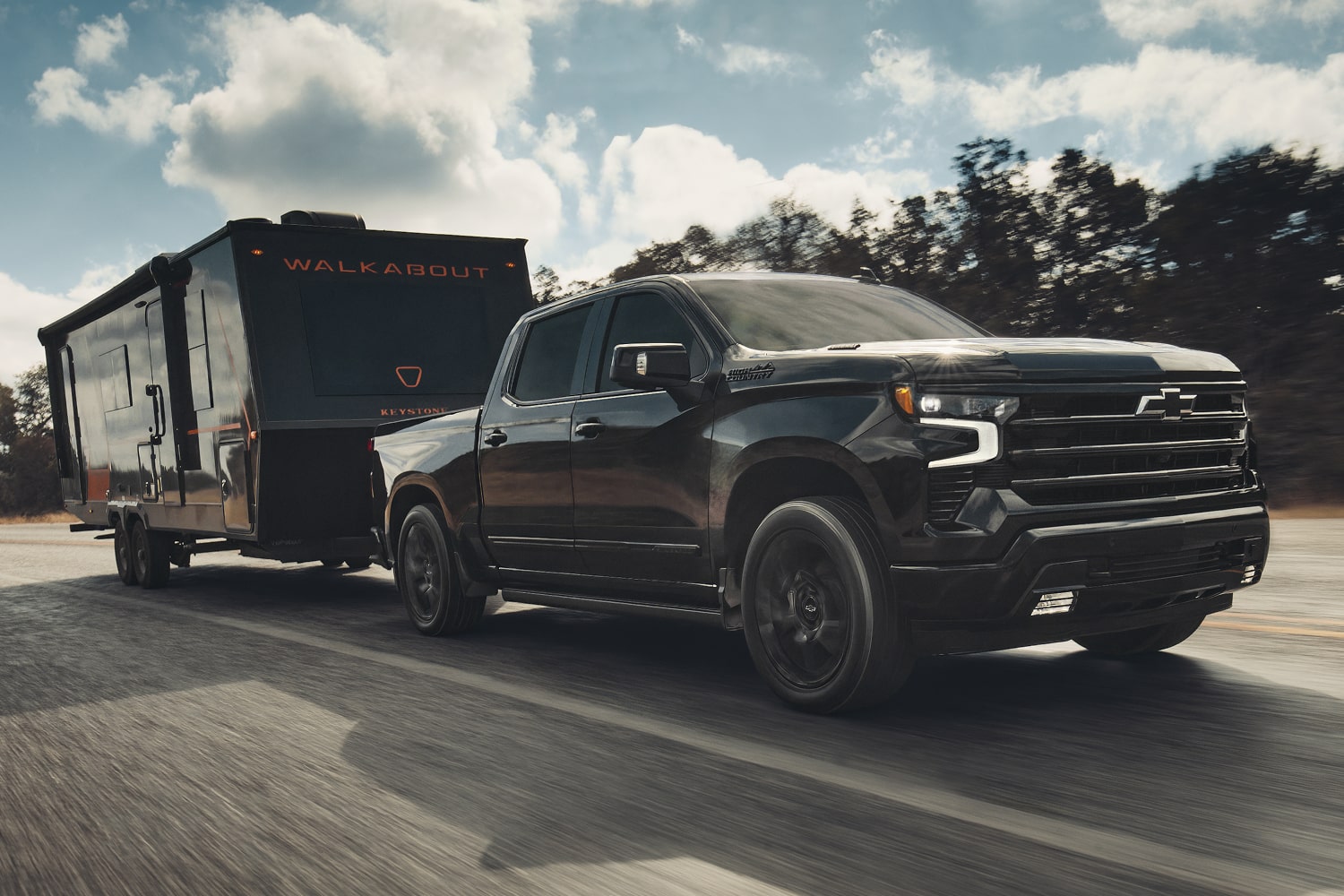 2026 Chevrolet Silverado LD towing an enclosed trailer on the road.