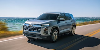 Three Quarters View of a White 2026 Chevy Colorado Driving through a Dust Cloud on a Desert