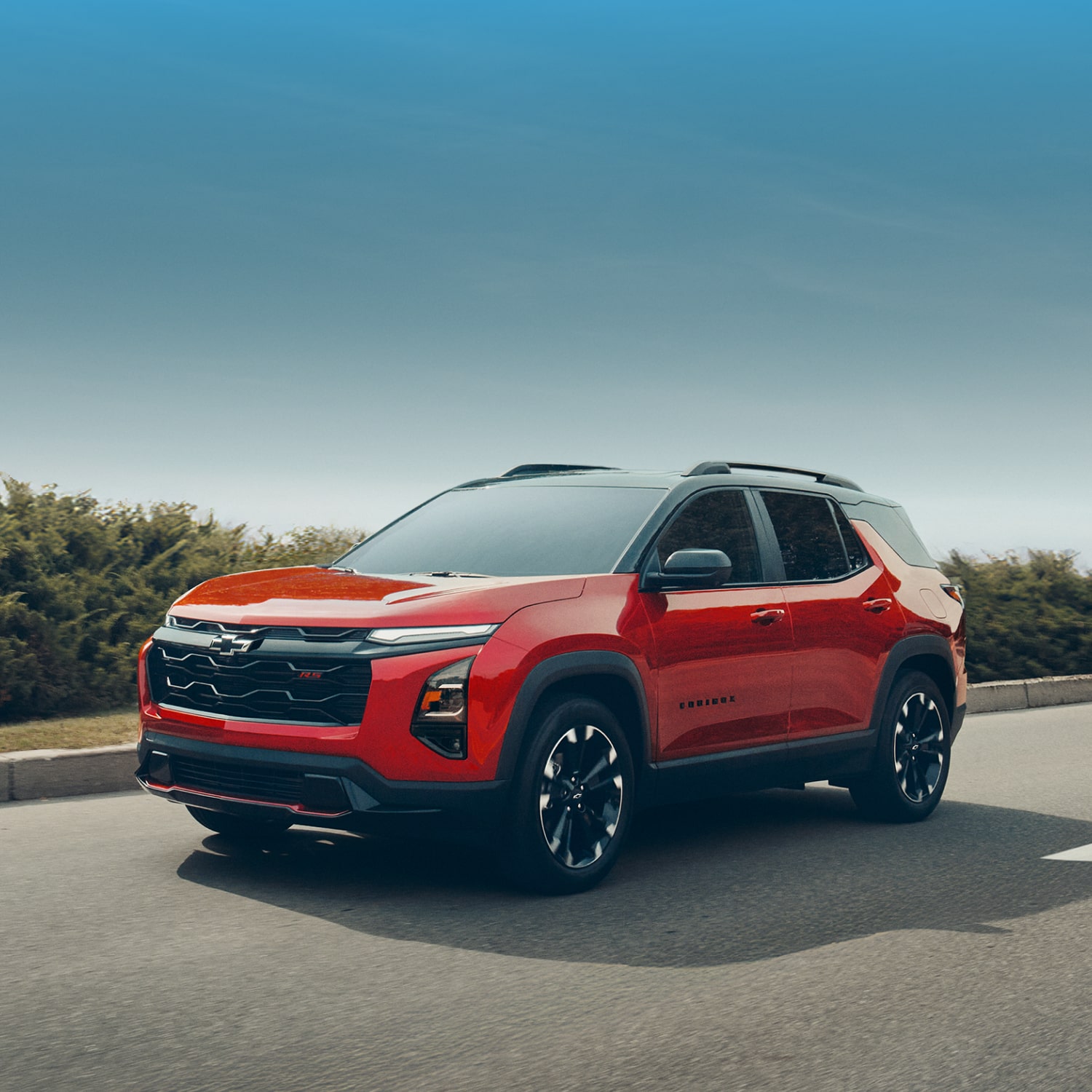 A Red 2027 Chevy Equinox Driving on a Street Lined with Bushes