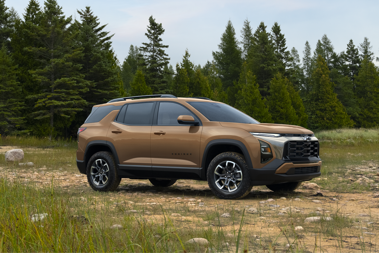 Bronze 2027 Chevrolet Equinox parked on a grassy clearing in front of evergreen trees