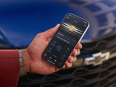 Close-up of Someone Holding a Phone Displaying the Chevy App with Text Overlay Reading "OnStar"