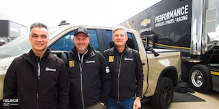 Tres hombres de pie posando para una foto con una camioneta Chevy ZR2 y un remolque de Chevy Performance al fondo