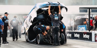 Vista amplia de un equipo de boxes inspeccionando un Funny Car de Chevrolet