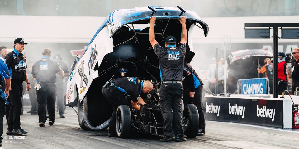 Vista amplia de un equipo de boxes inspeccionando un Funny Car de Chevrolet