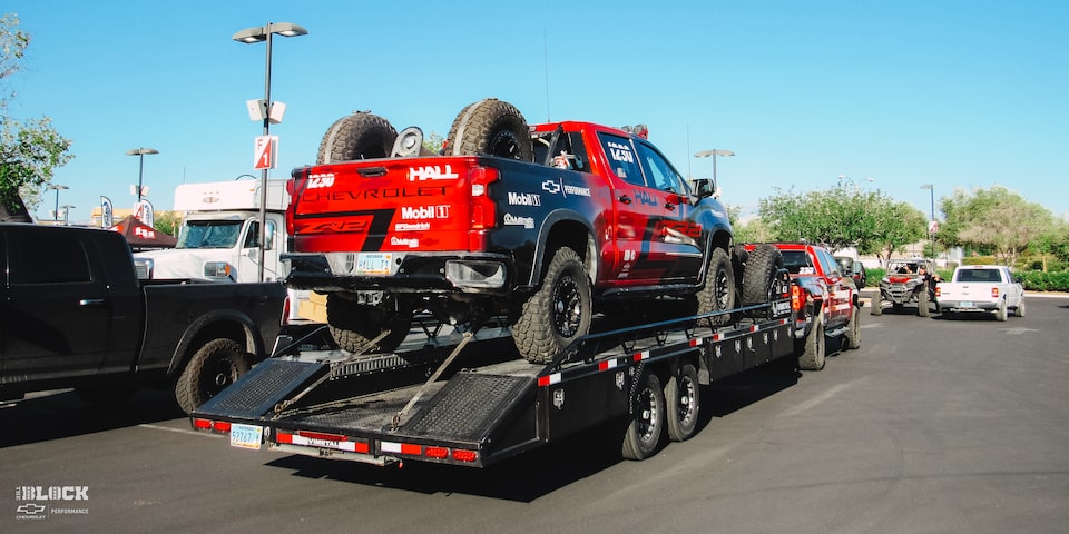 Rear Side View of Modified Off-Roading Chevrolet Silverado Truck Being Unloaded From a Trailer