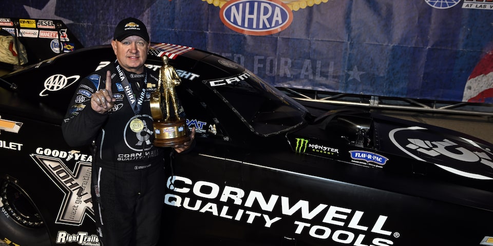 Front Three-Quarters View of Robert Hight Standing Next to His Race Car Holding a Trophy