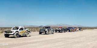 Lineup of Off-Roading Trucks Driving Through the Desert