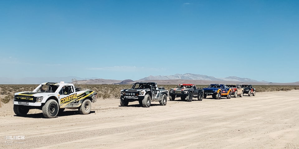 Lineup of Off-Roading Trucks Driving Through the Desert