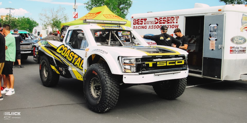 Front Side View of an Off-Road Chevy Truck Parked With People Standing Nearby