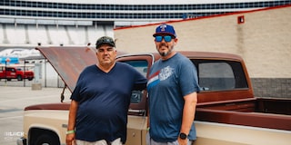 Dos hombres parados al lado de una camioneta Chevy C10 1983 supercargada