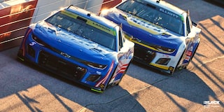 Team Chevy Driver Kyle Larson Driving on a Race Track Follwed Closely by Another Vehicle