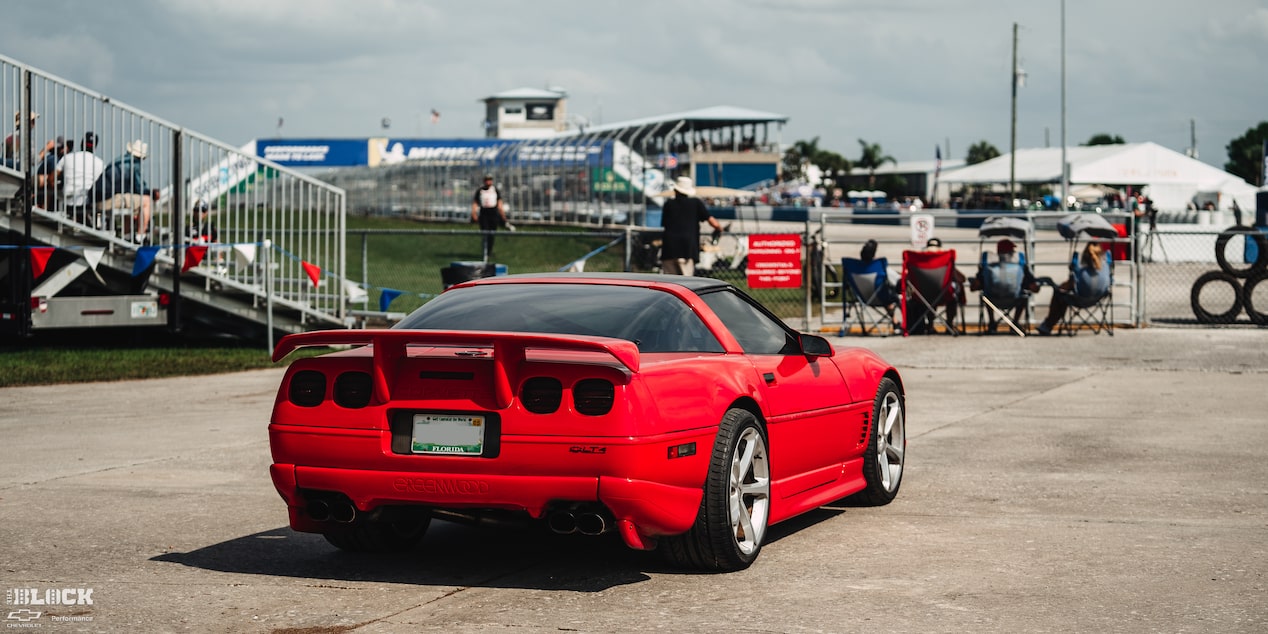 Rear View of Mitch Dixon's Red 1996 Green Corvette Parked in Front of a Race Track