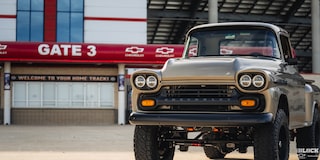 Three Quarters View of a Silver 1958 Chevy Apache Pickup Truck in Front of the Stadium Gate on the Right Side of the Frame