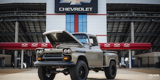Three Quarters View of a Silver 1958 Chevy Apache Pickup Truck with Its Hood Open in Front of the Chevy Stadium Gate
