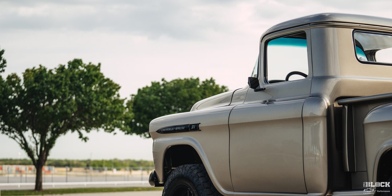 Three Quarters View of a 1958 Chevy Apache Pickup Truck on the Right Side of the Frame with Trees Seen in the Distance