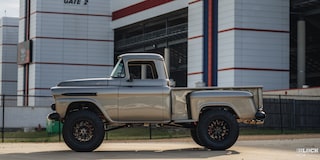 Side View of a Silver 1958 Chevy Apache Pickup Truck on a Sunny Day with a Building in the Distance
