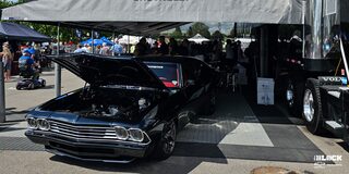 Three Quarters View of a 1969 Black Chevrolet Vehicle with Its Front Hood Open in a Tent for an Event