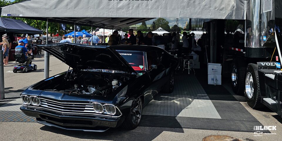 Three Quarters View of a 1969 Black Chevrolet Vehicle with Its Front Hood Open in a Tent for an Event