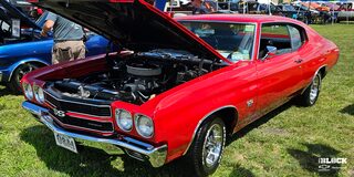 A Three Quarters View of a Red 1970 Chevy Chevelle with Its Hood Open in a Racing Event on a Grassy Plain