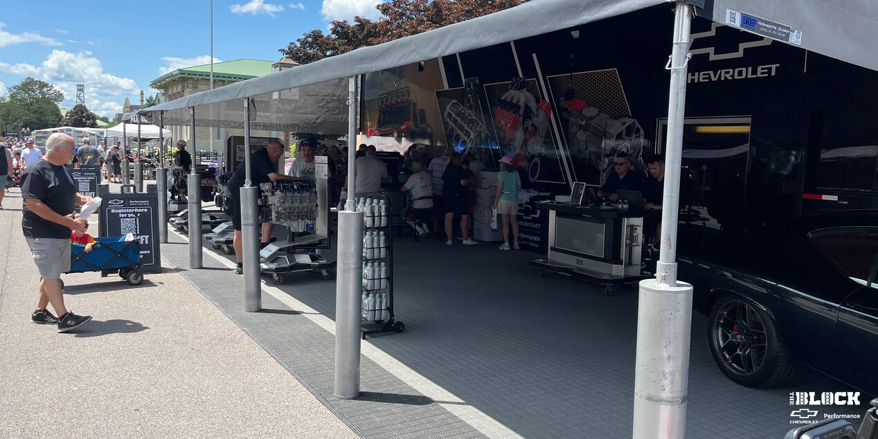 A View of a Tent with Various Car Parts, Vehicles and People Gathered Around