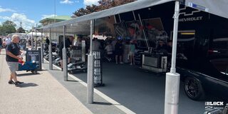 A View of a Tent with Various Car Parts, Vehicles and People Gathered Around