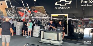 View inside a Tent with People Talking and Chevy Parts Posters and Displays in the Back