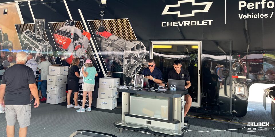 View inside a Tent with People Talking and Chevy Parts Posters and Displays in the Back
