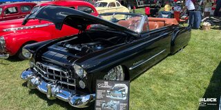 Three Quarters View of a Black Cadillac Series 62 with Its Front Hood Open on a Grassy Plain