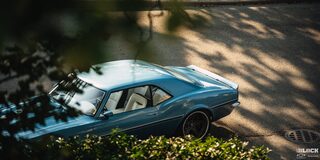 A Classic Blue 1968 Chevrolet Camaro Visible Through Brush