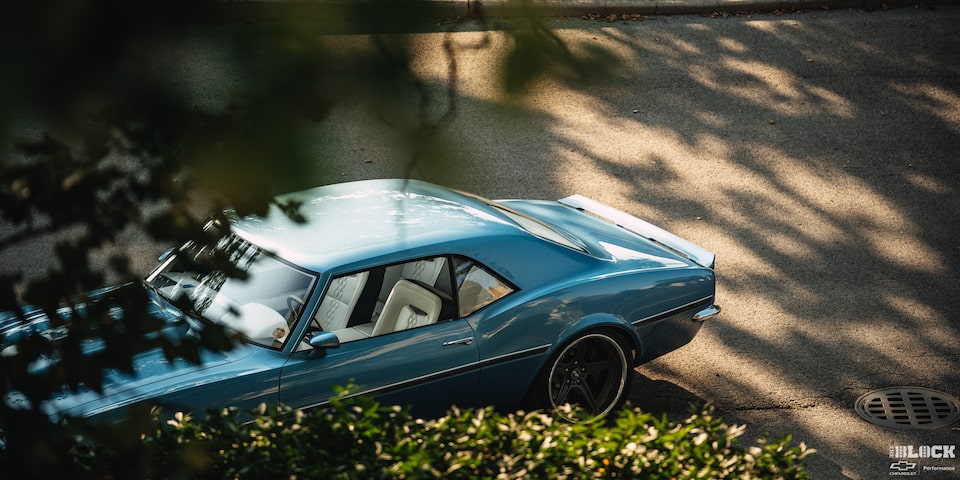 A Classic Blue 1968 Chevrolet Camaro Visible Through Brush