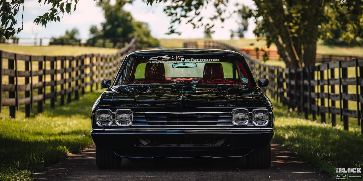 Front View of a 1969 Black Chevy Chevelle under a Shade with Fences and Grass on Both Sides