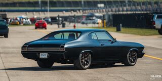 Three Quarters Rear View of a Black 1969 Chevy Chevelle Parked under a Sunny Sky at a Racing Event