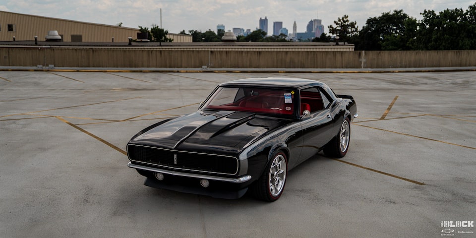 Three Quarters View of a Black 1968 Chevy Camaro Parked in an Empty Ground with Buildings Seen in the Distance