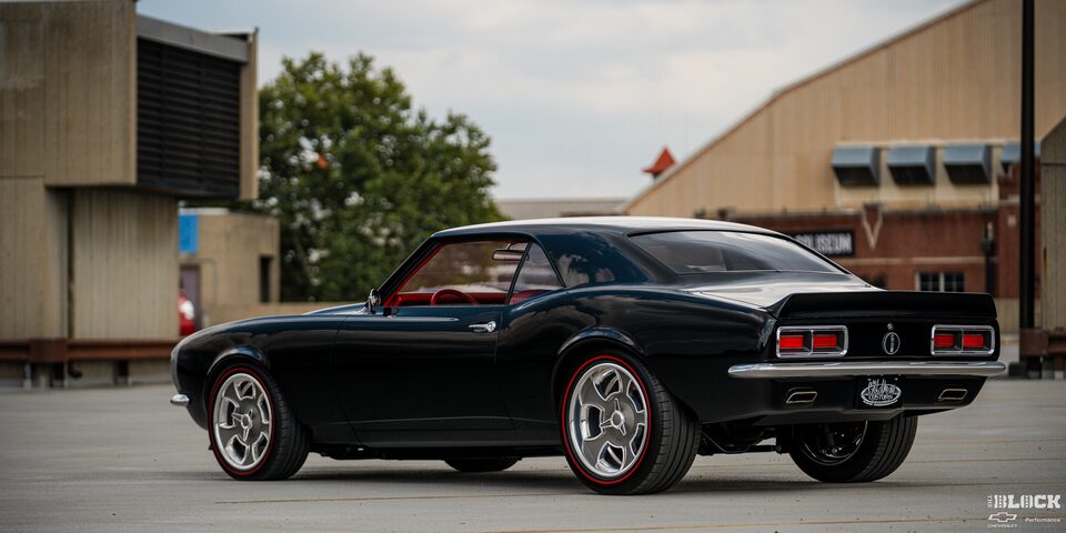 Three Quarters View of a Black 1968 Chevy Camaro Parked in an Empty Ground with Buildings Seen in the Distance
