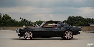 Side View of a Black 1968 Chevy Camaro Parked in an Emtpy Parking Lot with its Hood Open