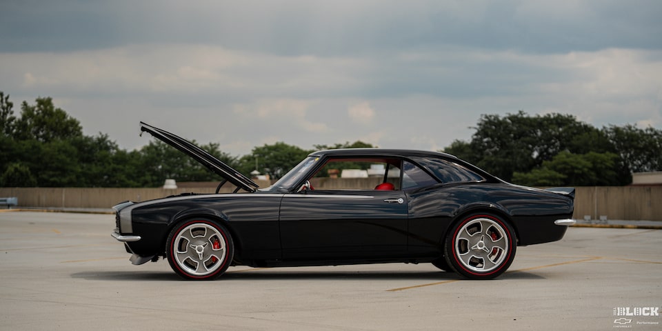 Side View of a Black 1968 Chevy Camaro Parked in an Emtpy Parking Lot with its Hood Open