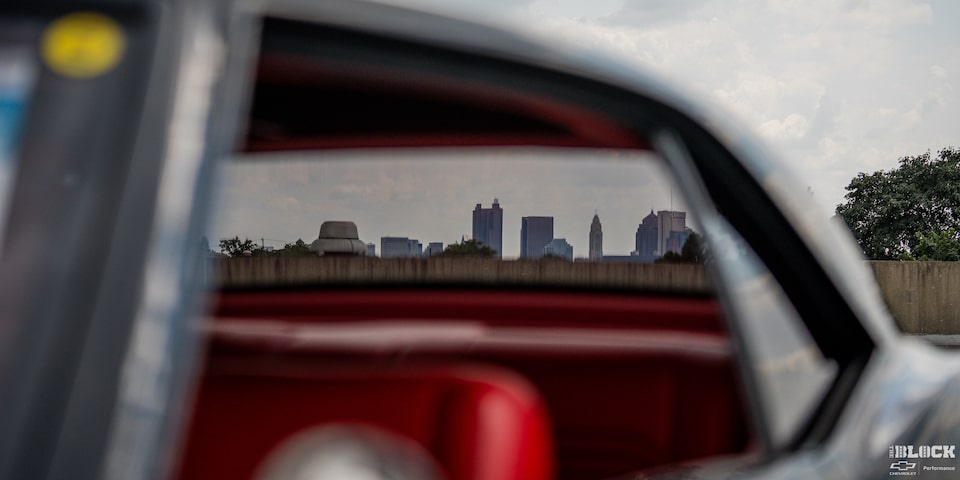 A View of Buildings in the Distance Seen through the Rear Window of a 1968 Chevy Camaro