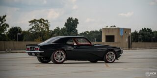 Side View of a 1968 Chevy Camaro under a Cloudy Sky with Trees in the Distance