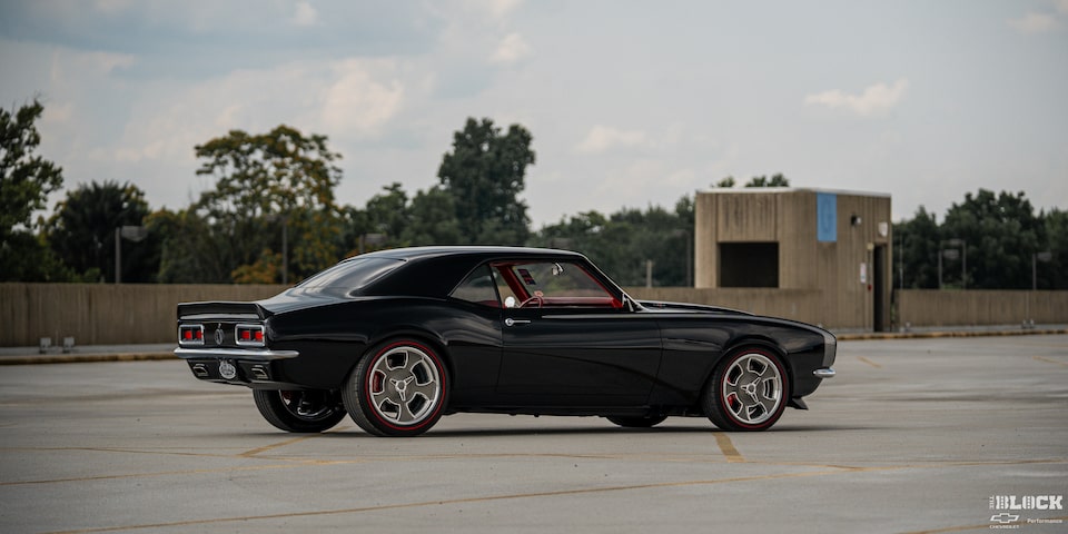 Side View of a 1968 Chevy Camaro under a Cloudy Sky with Trees in the Distance