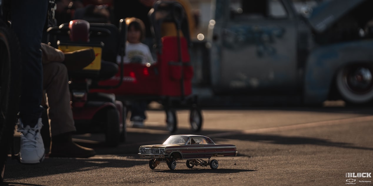 A Tiny Chevrolet Vehicle Toy on the Road with People Seen in the Background